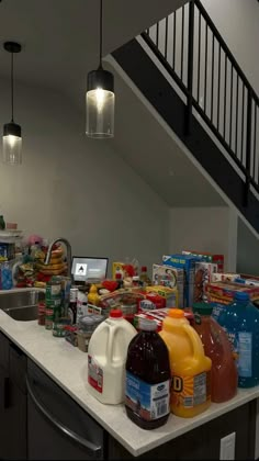 the kitchen counter is full of food and drinks, along with an open stair case