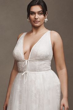 a woman in a white dress posing for the camera with her hands on her hips