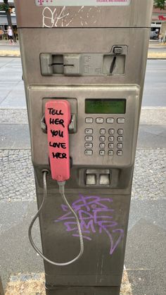 an old pay phone with graffiti on it