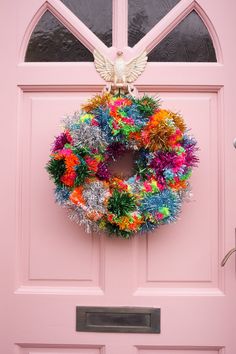 a pink door with a colorful wreath hanging on it