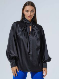 Polished femininity is a key detail in Tia Dorraine's designs, including this alluring blouse, crafted from a lustrous satin fabric in classic black. With an elegantly knotted, high neckline, oversized silhouette, and voluminous sleeves, this day-to-night design will remain a staple in your closet year after year.  Pair it with the Royal Azure Wide-Leg Trousers for an effortlessly elegant look. Hand wash only. Wash inside out with like colours. Do not wring or twist. Do not tumble dry. Iron at 1 Sleek Solid Blouse For Night Out, Sleek Satin Blouse For Date Night, Black Satin Tops For Evening, Elegant Silk Blouse For Date Night, Sleek Solid Silk Blouse, Luxury Silk Tops For Night Out, Luxury Silk Top For Night Out, Elegant Evening Satin Blouse, Silk Blouson Sleeve Evening Tops