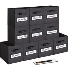 six black storage bins with labels on them and a pen in the middle one