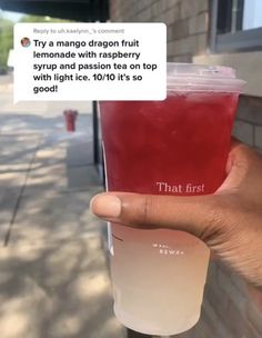 a person holding up a cup with tea in it on the sidewalk next to a building