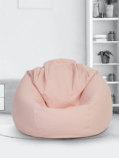 a pink bean bag chair sitting on top of a white floor next to a book shelf