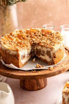 a cheesecake on a wooden platter with one slice cut out and ready to be eaten