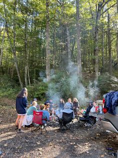 a group of people sitting around a campfire in the middle of a wooded area