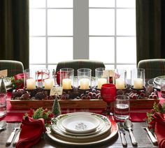 a christmas table setting with candles, plates and napkins