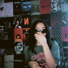 a woman with sunglasses covering her face in front of posters