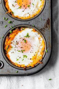 two eggs in a muffin tin with chives and seasoning sprinkles