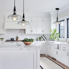 a large kitchen with white cabinets and marble counter tops, an island in the middle