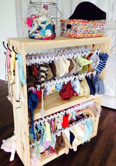 a wooden shelf filled with lots of baby clothes and hats on it's sides