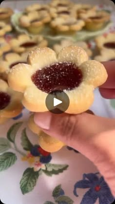 a person is holding up small pastries with jelly in the middle and on top