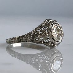 Details: Pretty Edwardian 18K white gold filigree .58 carat diamond ring from the 1920's! The filigree has beautiful sweet flowers in the 18K gold. The height of the ring sits up 5.9mm, and the diamond measures 5.8mm round x 2.78mm deep. Diamond is a VS1, Color J. This ring comes with an appraisal. Please ask all necessary questions prior to placing an order. Details from Appraisal: Cut: Transition/Round Brilliant Cut Carat Weight: .58 carat (estimated) Measurements: 5.8 x 2.78mm Color: J Clarit Formal Diamond Filigree Ring With Diamond Cut, Vintage Jewelry With Filigree And Round Cut, Vintage Jewelry With Filigree, Classic Filigree Diamond Promise Ring, Formal Diamond Filigree Ring With Brilliant Cut, Diamond Filigree Ring With Brilliant Cut For Formal Occasions, Elegant White Gold Engraved Ring With Rose Cut Diamonds, Elegant Engraved White Gold Ring With Rose Cut Diamonds, Art Deco Style Diamond Filigree Ring For Formal Occasions