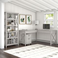 a white desk sitting under a window next to a book shelf