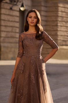 a woman in a brown dress posing for the camera with her hands on her hips