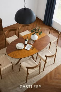 a wooden table with chairs and vases on it next to a lamp hanging from the ceiling