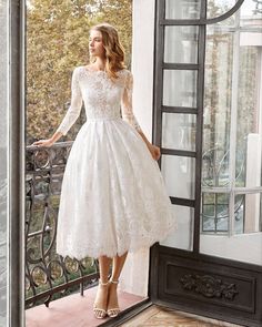 a woman in a white dress standing on a balcony