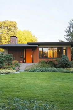 a house that is in the middle of some grass and bushes with trees around it