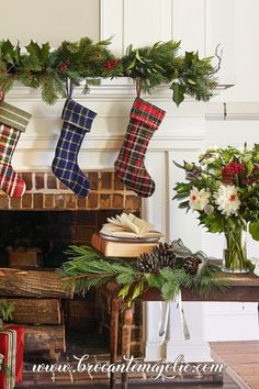 christmas stockings hanging from a mantel decorated with greenery