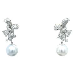 18K White Gold Pearl Earrings with Diamonds 2 White Pearls 12mm 116 Diamonds - 1.48 CT 18K White Gold - 8.69 GM Adorn yourself with timeless elegance in these 18K white gold pearl earrings, exuding sophistication and grace. Each earring features two lustrous 12mm white pearls, symbolizing purity and beauty, embraced by a dazzling array of 116 diamonds totaling 1.48 CT. The intricate craftsmanship and attention to detail elevate these earrings to a level of unparalleled luxury. Crafted with 18K w White Gold Pearl Earrings, Pearl Drop Earrings Gold, Gold Pearl Earrings, Diamond Drop Earrings, Gold Pearl, Pearl Drop, Pearl Drop Earrings, Pearl White, Essence