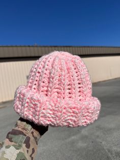 a person wearing a pink knitted hat in front of a building on a sunny day