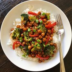 a white plate topped with rice, broccoli and chickpeas next to a fork