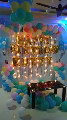 a birthday party with balloons and streamers on the wall, lights in the background