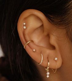 a woman wearing three different types of ear piercings