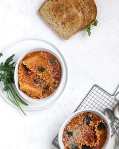 two bowls of pasta with bread on the side