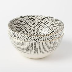 two white and black bowls with gold trims on the sides, one is filled with dots