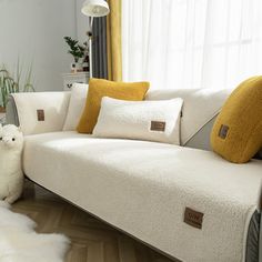 a white couch with yellow pillows and a sheep rug on the floor next to it