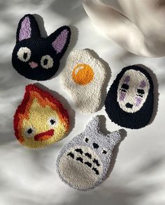 four crocheted animal faces are shown on a white sheet with a flower in the background