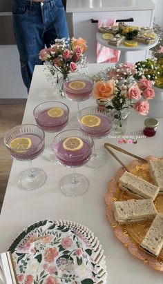 a table topped with plates and glasses filled with desserts on top of a white table