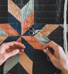 two hands working on a quilt with scissors