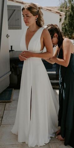 a woman in a white dress standing next to another woman with her hand on her hip