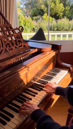 a person playing the piano in front of a window