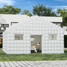 an inflatable house sits on the side of a brick road next to a white building