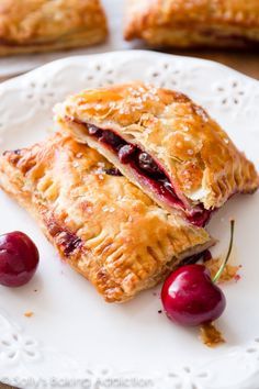 two cranberry turnovers on a white plate with cherries