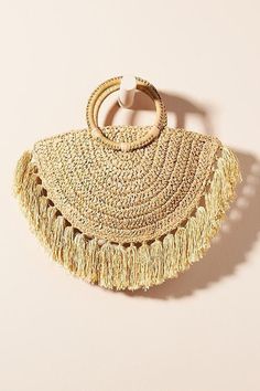 a straw bag with tassels hanging from it's side on a white surface