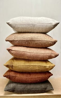 five pillows stacked on top of each other in different colors and sizes, with the same color