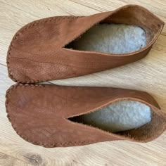 the inside of a pair of brown shoes on top of a wooden floor next to a white ball