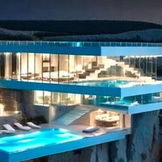 a large house with a swimming pool in the middle of it at night, surrounded by mountains