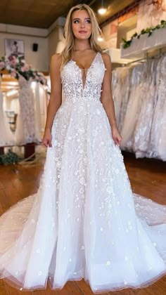 a woman wearing a white wedding dress standing in front of dresses on display at a bridal