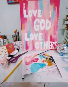 some art supplies are on a table with a sign that says love god love others