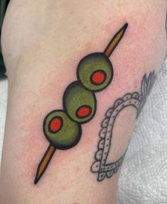 a tattoo with an olive on it and a toothpick in the shape of two olives