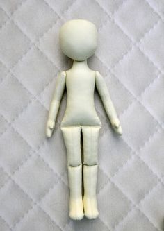 a white doll sitting on top of a bed