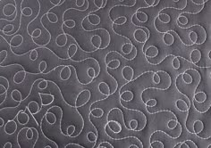 closeup of the stitchs on an embroidered quilted material that looks like wavy lines