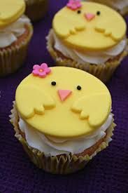 cupcakes decorated with yellow frosting and pink bows are arranged on a purple surface