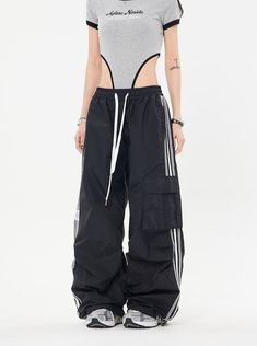 Our Striped Wide Leg Track Pants combine classic style with a relaxed fit for effortless comfort. Made with an elastic drawstring waistband and a striped pattern, these pants are perfect for weekend lounging at home or a casual day out. Model is 5'2 100lbs wearing M Sporty High-waisted Drawstring Bottoms, Black Drawstring Leisure Pants, Black Relaxed Fit Sweatpants For Summer, Black Leisure Trousers, Sporty Parachute Pants For Leisure, Black Cargo Pocket Pants For Loungewear, Black Wide-leg Parachute Pants For Loungewear, Athleisure Pants With Contrast Stripes For Spring, Spring Athleisure Pants With Contrast Stripes