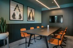 an empty conference room with orange chairs and a large table in front of a blackboard